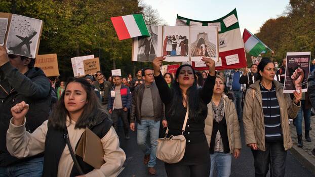 Demonstrant*innen mit Transparenten und Schildern, die Frauenrechte im Iran fordern.